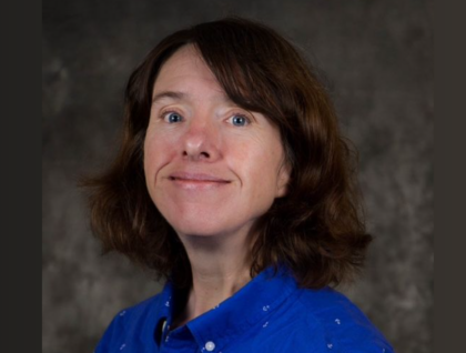 Person with shoulder length brown hair smiling with a blue shirt